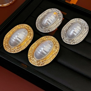 Detailed view of vintage oval pearl earrings in gold and silver with hammered metal texture