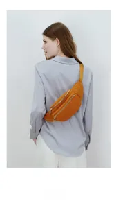 Detail of amber yellow corduroy chest bag showing vertical texture and dual gold zippers