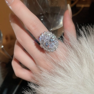 Close-up of a silver-plated ring with a large oval zircon and double halo on finger
