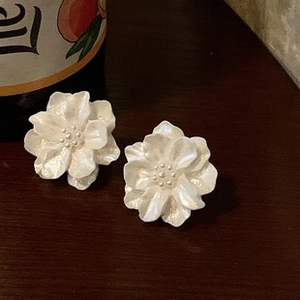 Detailed macro shot of French baroque white flower earrings with pearlescent satin finish