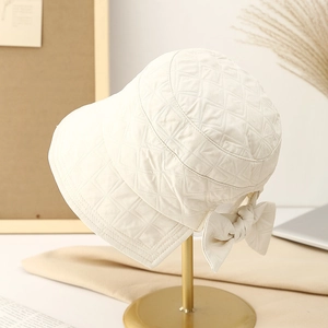 Japanese style quilted bucket hat in cream white with a back bow on a gold display stand