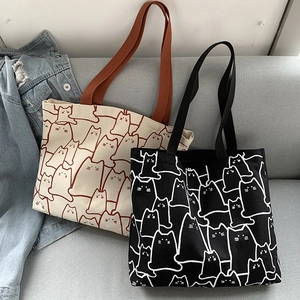Detail of canvas tote bags featuring minimalist cat pattern on a grey fabric sofa