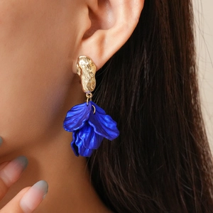 Close-up of model wearing gold hammered earrings with large blue acrylic floral petals