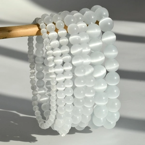 Close-up of multilayered white cat eye stone beaded bracelets in various bead sizes