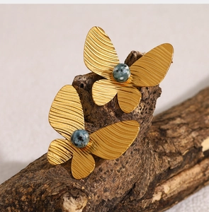 Macro shot of 18K gold-plated butterfly earrings with African turquoise on natural wood