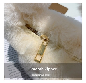 Close-up of smooth gold metal zipper on soft white faux fur plush handbag with elegant detail