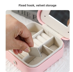 Detail of adjustable dividers and jewelry hooks inside the pink storage box with mirror