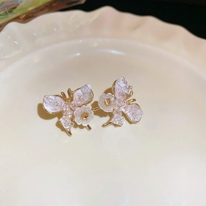 Detail shot of butterfly floral earrings with crystals on a white ceramic tray
