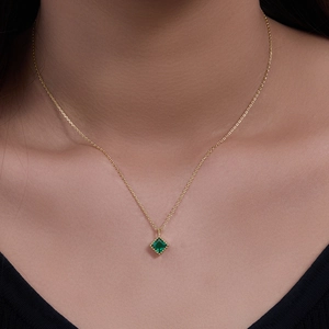 Luxurious gold necklace with square emerald zircon pendant worn on a model neckline