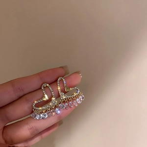 Gros plan de boucles d'oreilles cœur en or avec zircones sur fond beige doux