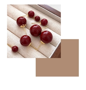 Macro detail of red sphere earrings with gold pins in various sizes on fabric