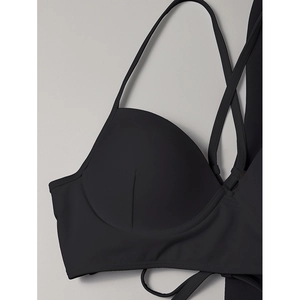 Bikini trois pièces noir avec fines bretelles et bonnets moulés sur fond gris neutre