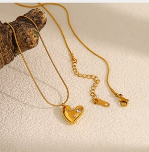 Macro shot of 18K gold heart pendant with sparkling crystals and sleek snake chain