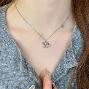 Gros plan du collier cheval à bascule argenté élégant avec zircons porté par un mannequin