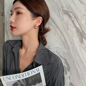 Close-up of minimalist silver double sphere stud earrings worn by a model