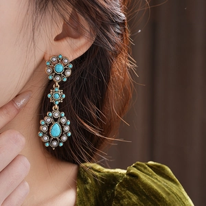 Detailed close-up of vintage gold drop earrings with turquoise stones and white pearls