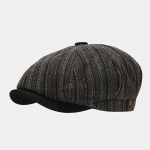 Detailed close-up of British style newsboy cap with herringbone pattern and metal side button