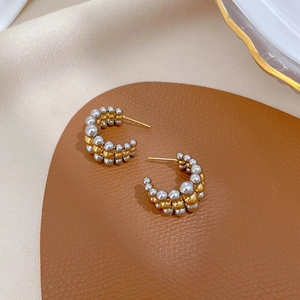 Detail of two-tone gold and silver beaded C-hoop earrings on premium textured leather