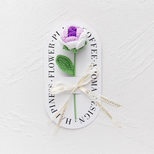 Detail of hand-knitted purple and white rose with Love Is Eternal ribbon and decorative card