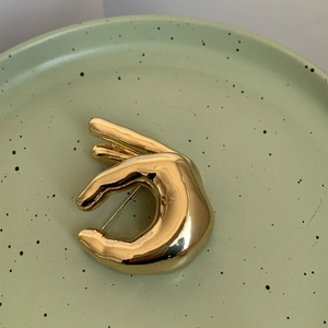 Gros plan détaillé d'une broche main dorée vintage avec une finition polie effet miroir