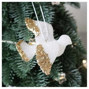 Close-up of a white glitter pigeon ornament hanging on a lush green Christmas tree
