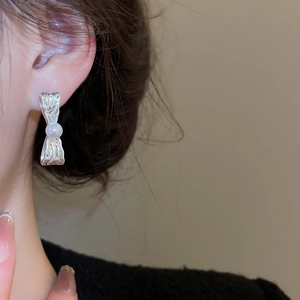 Primo piano di orecchini a fiocco in metallo con perle indossati per un look elegante