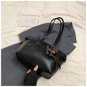 Detail of black faux leather tote bag with brown cartoon charms on gray blazer
