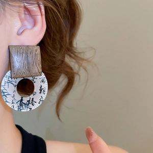 Close-up of wooden square earrings with bamboo ink painting on a model