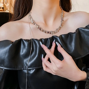 Close-up of silver sequin tassel necklace on model wearing black off-shoulder leather