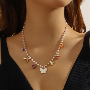 Vintage pearl necklace with golden butterfly, bee, and cherry pendants on a model
