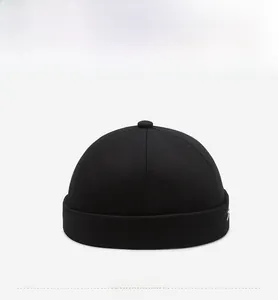 Detail of black cotton docker hat featuring small white embroidered letters on the side