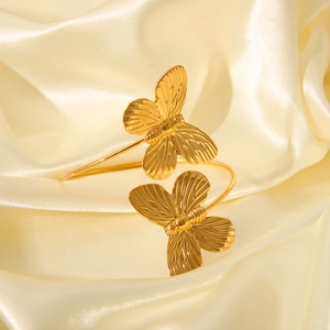 Macro shot of gold butterfly arm cuff bracelet on luxurious silk fabric background