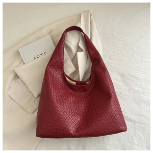 Detailed close-up of dark red woven leather tote bag on a blazer and arts book