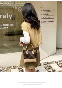 Macro detail of brown plaid tote bag with gold chain strap and synthetic leather base