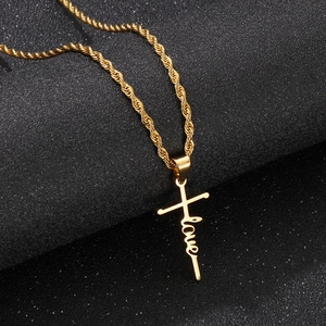 Nahaufnahme der goldenen Kreuzkette mit Love-Schriftzug auf grauem Hintergrund