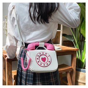 Unique white and pink rotary telephone shaped PU leather crossbody bag worn by a model