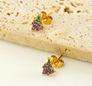 Macro view of gold grape stud earrings with purple zircons and green leaf gemstone