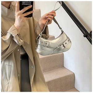Metallic silver chic underarm bag with industrial buckles and eyelets in urban setting