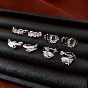 Macro shot of silver zircon snake and u-shaped ear cuff jewelry set on black leather