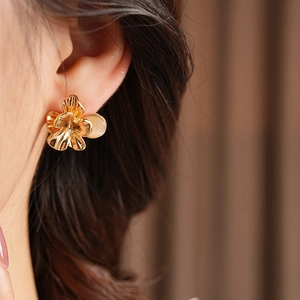 Close-up of vintage golden flower earring with cat-eye stone on a model's ear