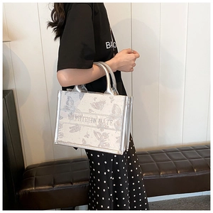 Detail of silver tote bag featuring butterfly print and embroidered horizontal band