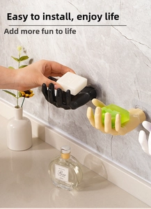 Detail showing palm-shaped wall hooks in black, beige, and white on marble wall