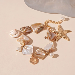 Close-up of golden starfish and seashell charms on a beach style pearl bracelet