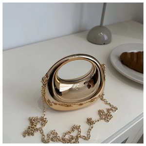 Gros plan de l'élégant sac de soirée en métal doré avec chaîne sur une table blanche