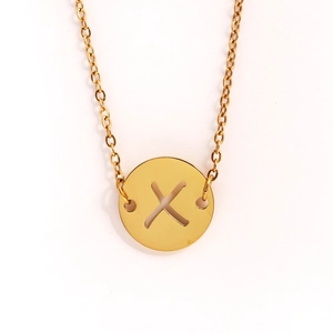 Gros plan d'un collier doré en acier inoxydable avec pendentif pièce ajouré lettre X