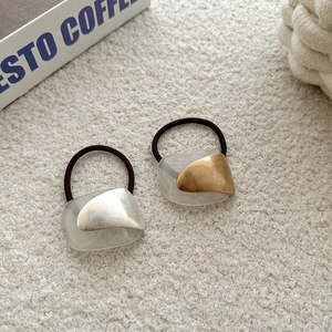 Minimalist hair ties with metallic gold and silver accents on elegant beige fabric