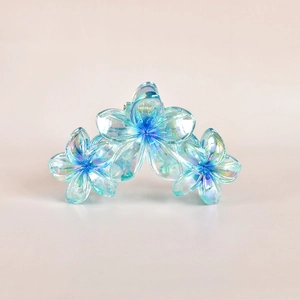 Detailed view of iridescent blue and green floral hair claw clip with transparent finish