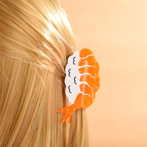 Detail of creative shrimp sushi hair claw clip with acetate finish on blonde hair
