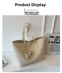 Detalle del bolso tote blanco roto con estampado de letras M y colgante de perrito