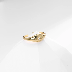 Macro detail of gold flower ring with center white zircon on white geometric stand